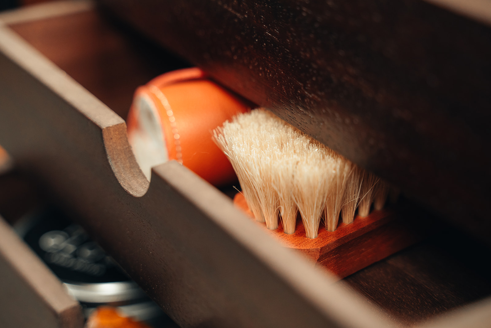 Brosse en poils naturels et cirage rangés dans un tiroir en bois, outils de soin pour chaussures en cordonnerie.