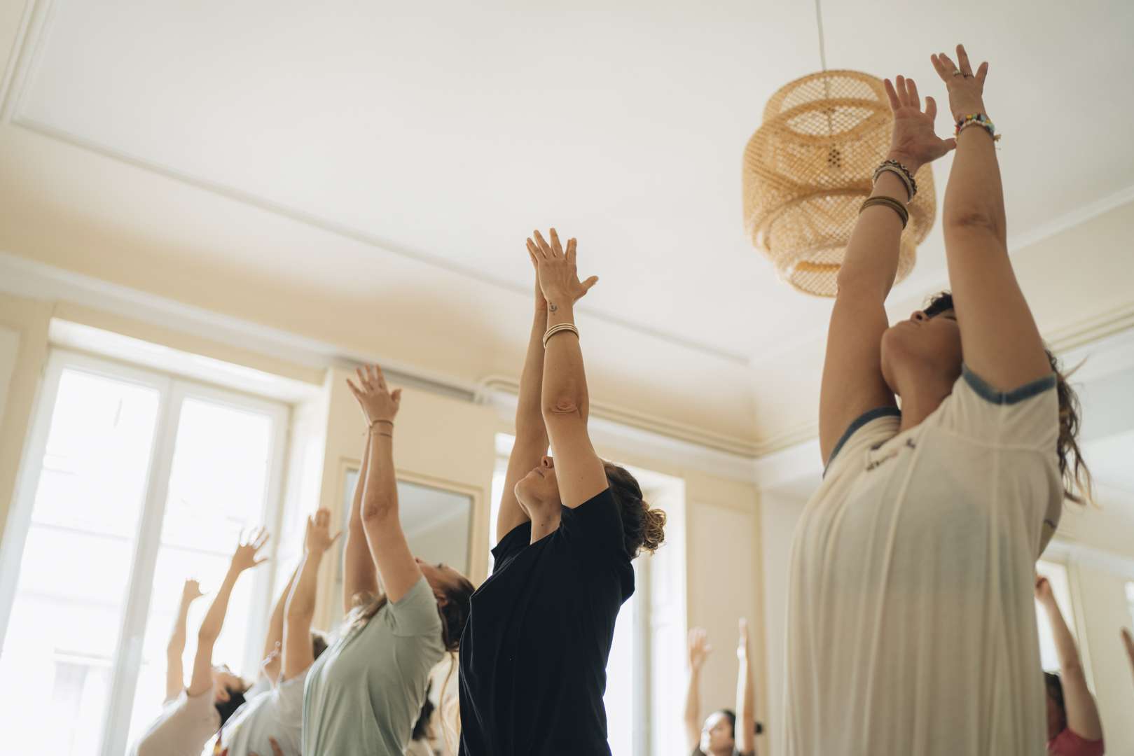 groupe de personnes bras levés dans un studio de yoga lumineux