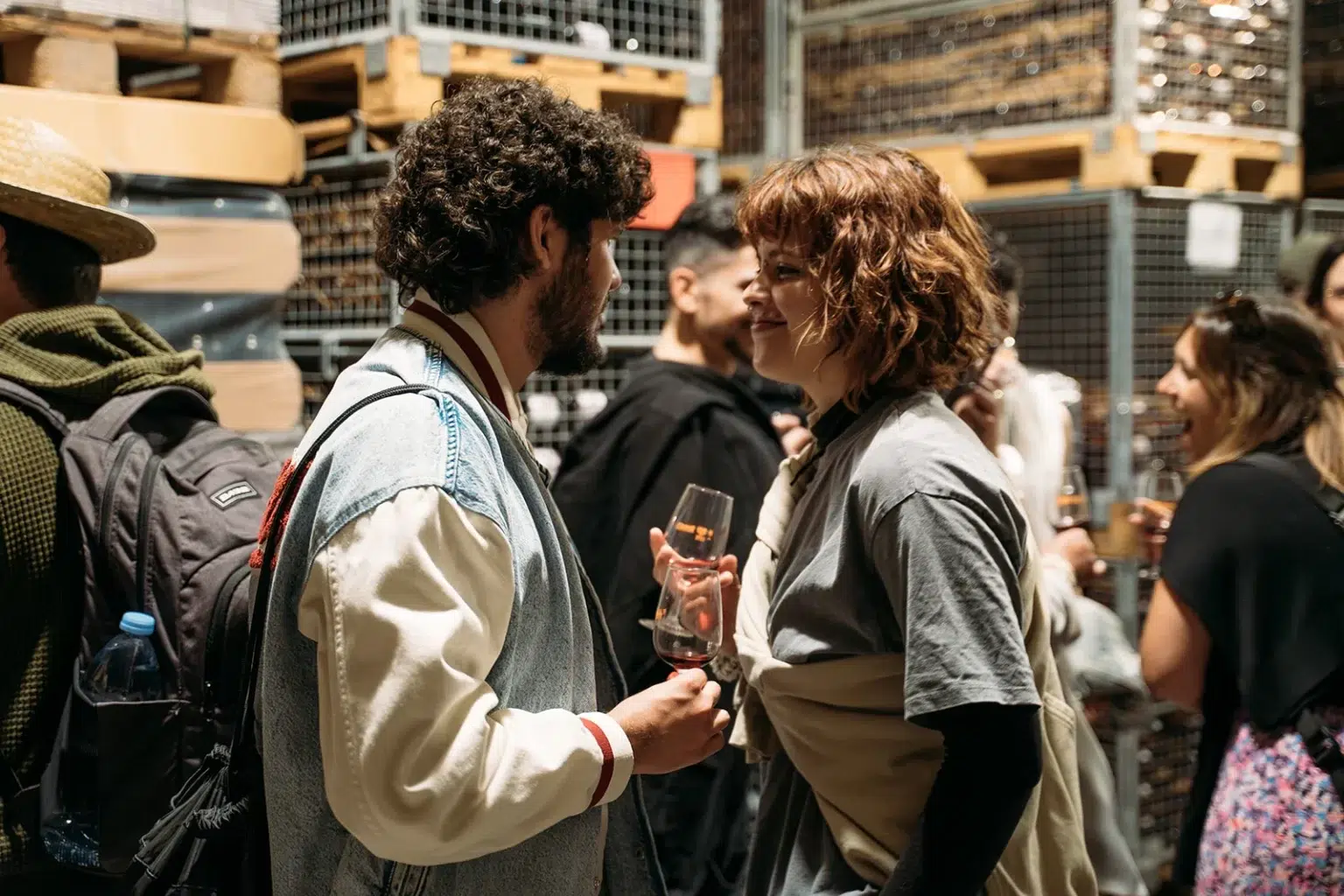 Discussion conviviale entre deux personnes avec un verre de vin à la main, ambiance détendue.