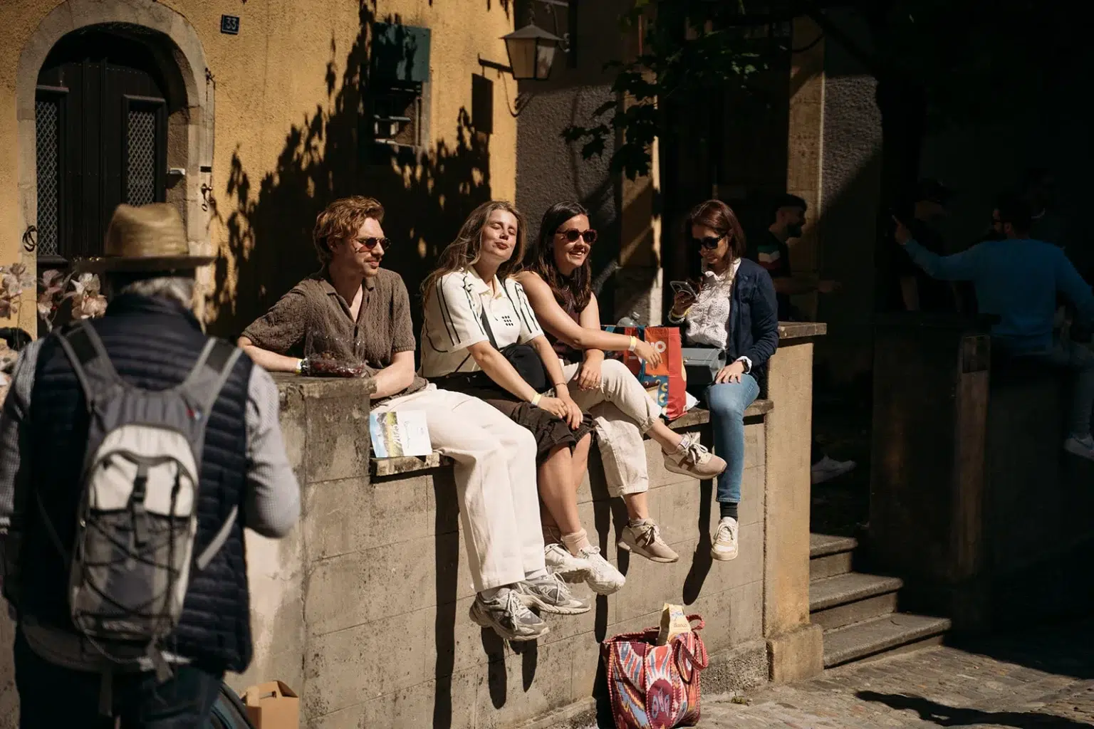 Groupe de jeunes femmes assises sur un muret, profitant du soleil et de l’ambiance des Caves Ouvertes.