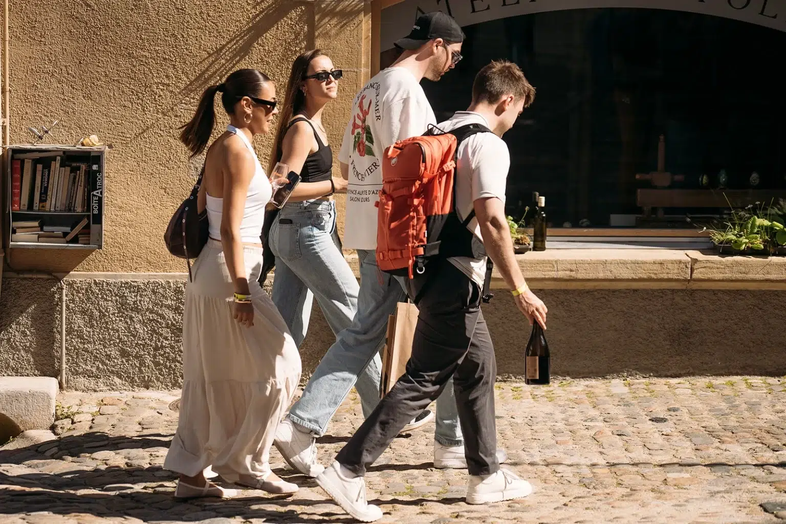 Groupe de personnes marchant dans une ruelle ensoleillée pendant les Caves Ouvertes 2025.