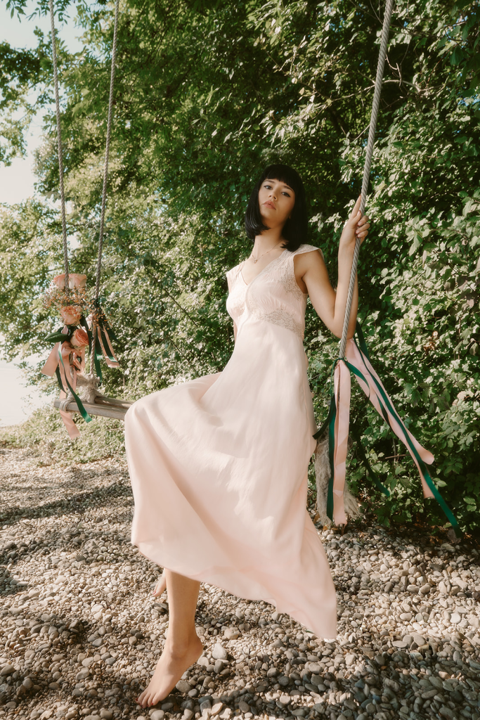 Modèle portant une robe rose poudré et un bijou Diane Gem’s by Alice Leloir sur une balançoire au bord du lac de Neuchâtel, photo de Sarah Adatte
