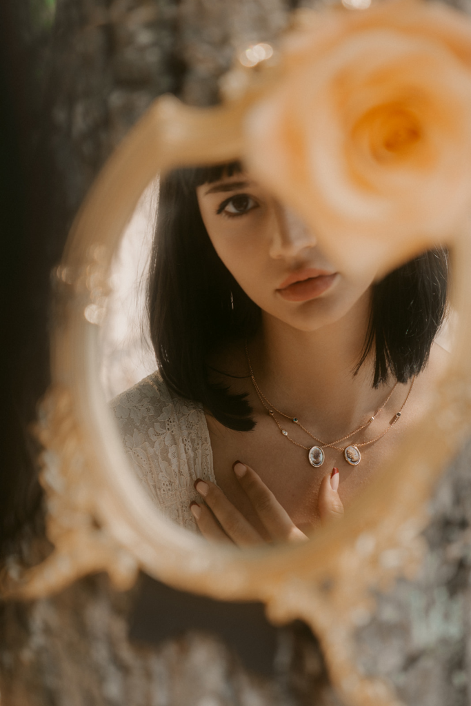 Portrait d’une femme se reflétant dans un miroir doré, portant un collier Diane Gem’s by Alice Leloir, photographie de Sarah Adatte